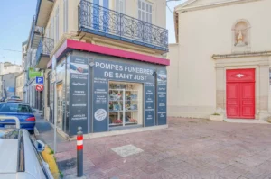 Façade et devanture de l'agence des Pompes Funèbres de Saint Just sur une place pavée