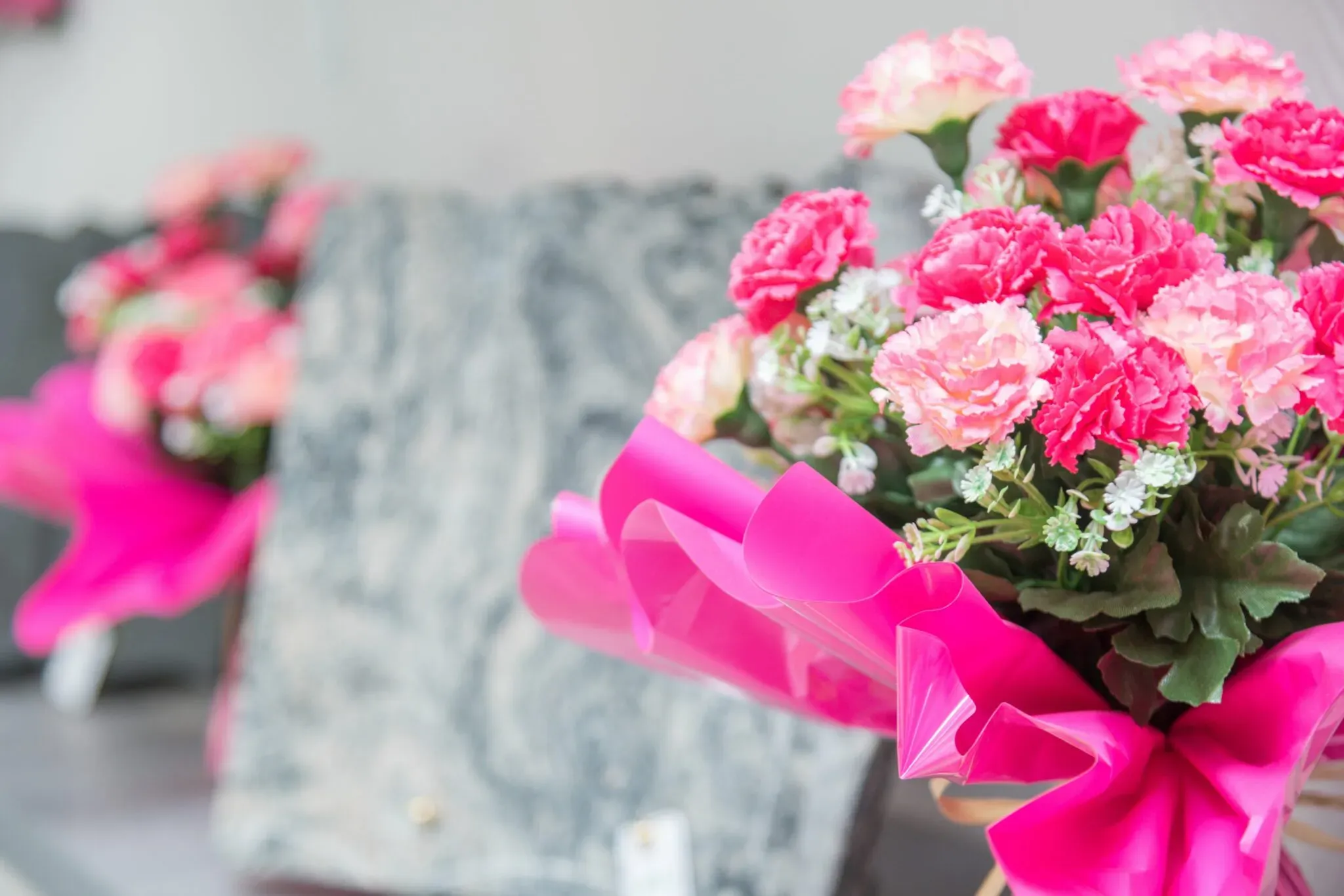Gros plan sur un bouquet de fleurs artificielles roses avec plaque de marbrerie en arrière-plan