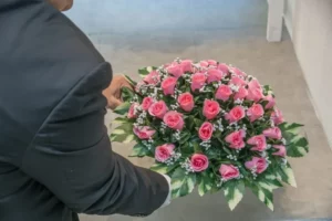 Personne tenant une imposante composition florale de roses roses et de gypsophile
